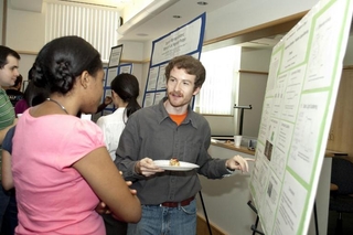 Undergraduate student talking to a visitor in front of his poster