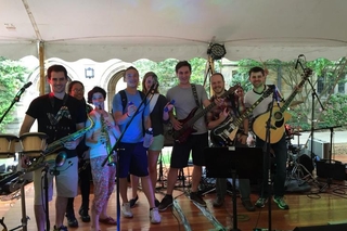 Large group of REU students holding a variety of musical instruments