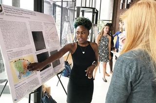 Undergraduate student talking to a visitor in front of her poster