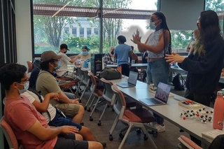 REU students talk to a small group of kids during an outreach activity