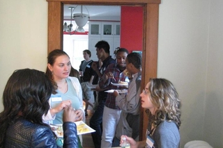 Small group people standing in a circle, talking, and eating snacks