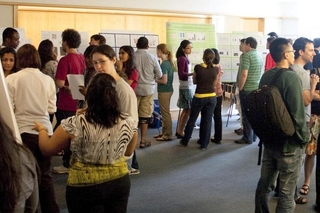 Around 15 people in a large room with posters on the perimeter of the room