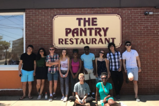 Group of REU students standing in front of the sign for the Pantry