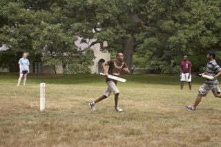 Two students run toward each other while playing cricket