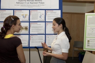 Undergraduate student talking to a visitor in front of her poster