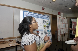 Undergraduate student talking to a visitor in front of her poster