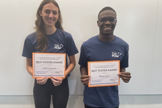 Anika and Michael holding their poster award certificates