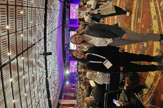 PEB students Lauren and Esther standing in a conference center