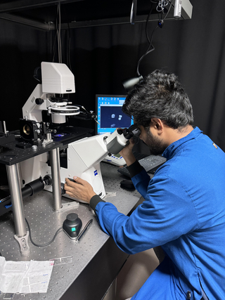 Raibat looking into the microscope in lab