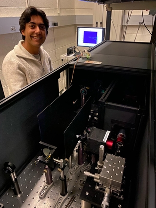 Rohin in a lab coat standing at the microscope